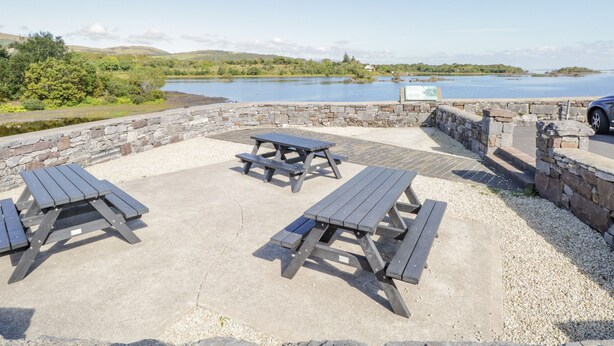 Un espace de pique-nique avec des murs en pierre et des bancs donnant sur un lac.