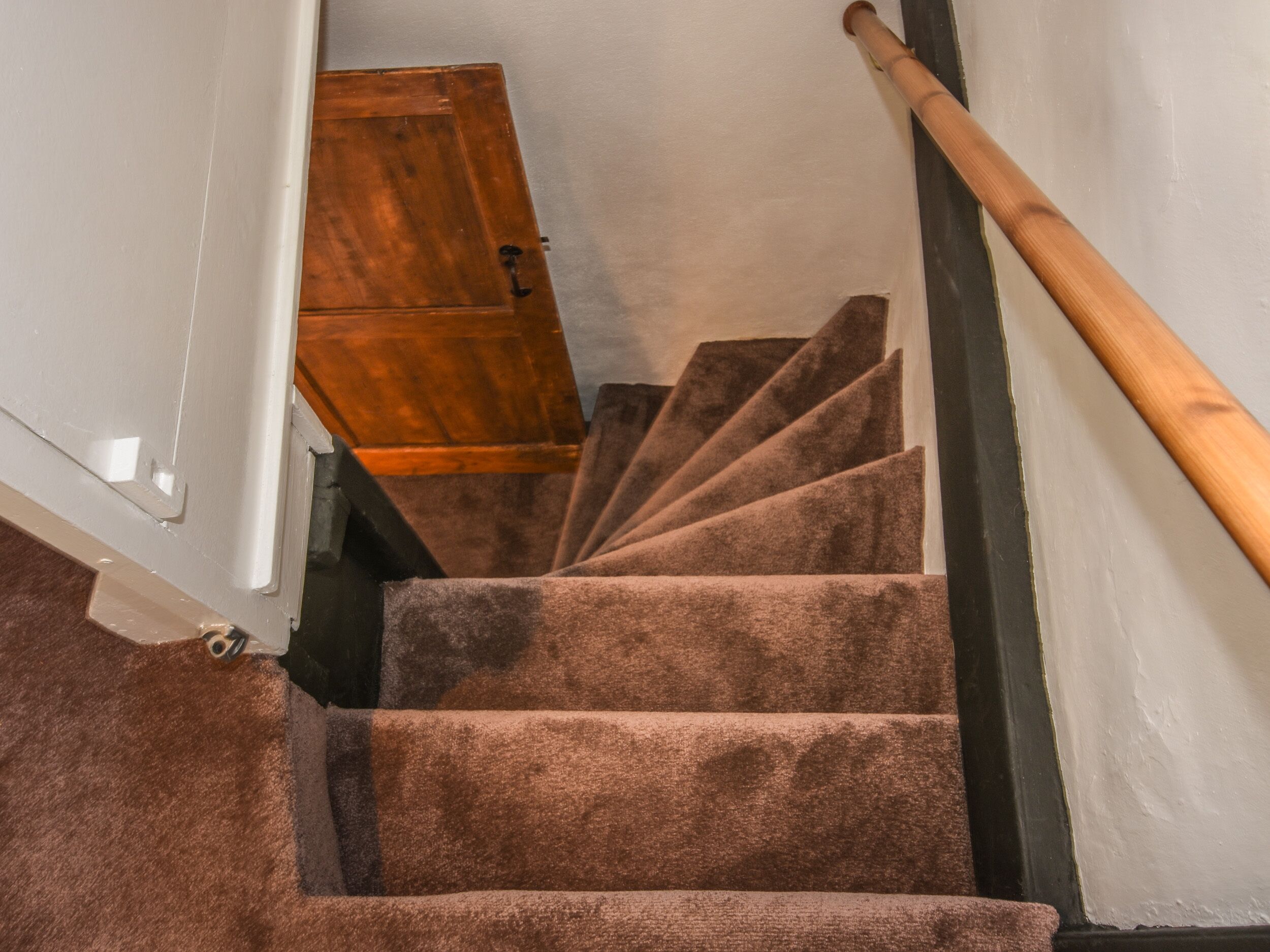 A staircase with carpeted steps and a wooden handrail.