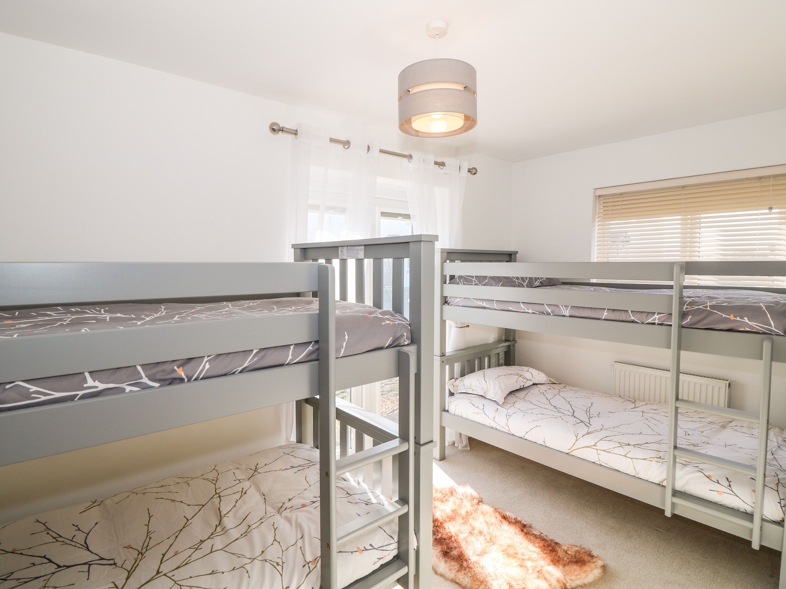 A bunk bed room with a grey color scheme, a white radiator, and a ceiling light fixture.