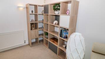 A room with a built-in wooden bookshelf, a radiator, and a white chair.