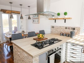 Una cocina moderna con una isla central, horno empotrado y un área de comedor con sillas y mesa.