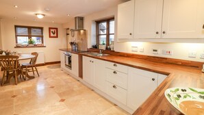 Una cocina con armarios blancos, una encimera de madera y una zona de comedor con mesa y sillas.