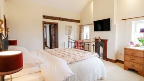 Un dormitorio con cama, cómoda, espejo, televisor y ventana con vistas.
