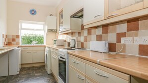 A kitchen with a window, a sink, a dishwasher, a stove, and a toaster. - Gull Cottage (Tintagel)