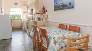 A kitchen with a dining table, chairs, and a painting on the wall. - Gull Cottage (Tintagel)