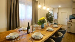 Comedor con mesa de madera dispuesta para cuatro, con platos, vasos y cubiertos.