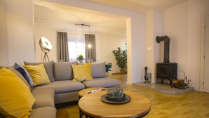 Una sala de estar con sofá, una mesa de centro redonda de madera y chimenea.