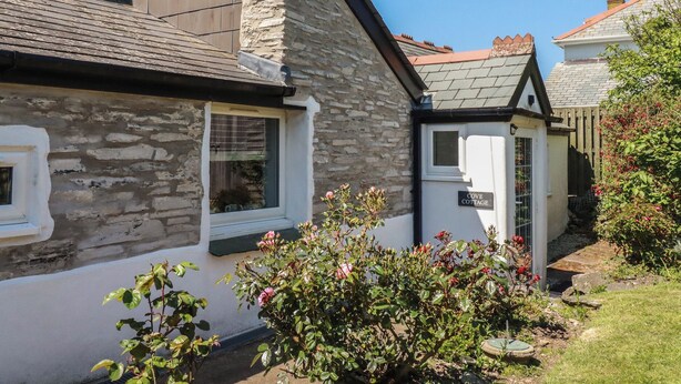 A stone cottage with a small garden, a visible window, and a door labeled 'COVE COTTAGE.' - Cove Cottage (Tintagel)