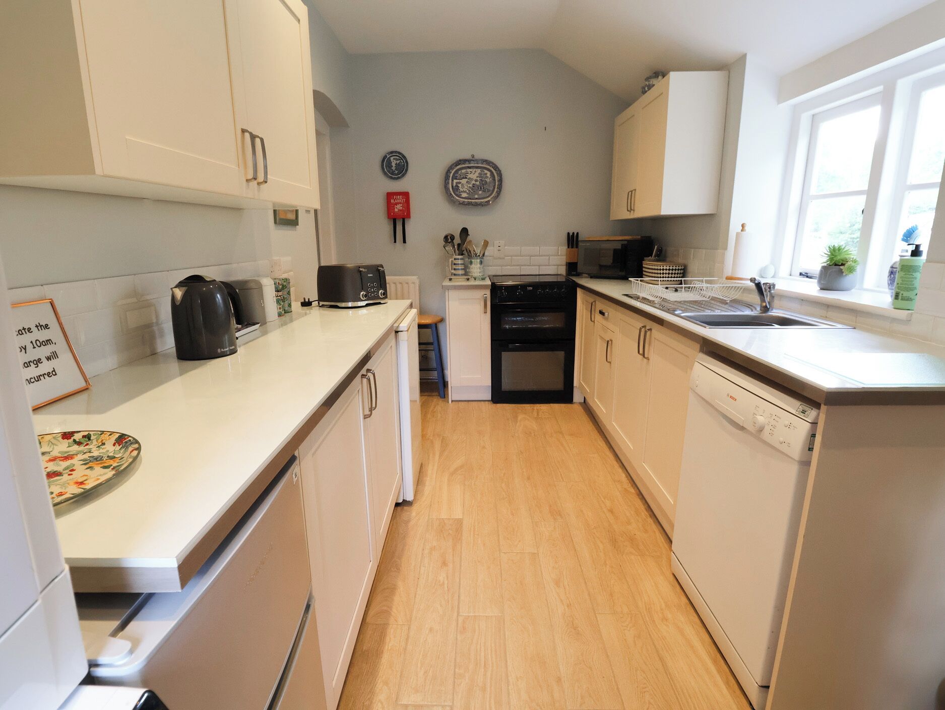 A kitchen with white cabinets, a toaster, a kettle, a stove, and a dishwasher.