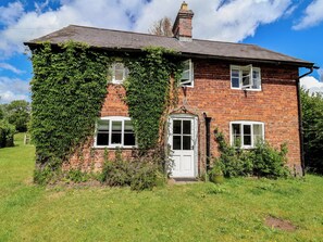 A brick house with ivy covering the walls, a white door, and two windows. - Wolvesacre Mill Cottage (Whitchurch)