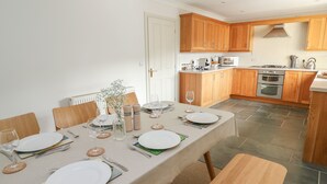 A modern kitchen with wooden cabinets, a dining table set for four, and a built-in oven.