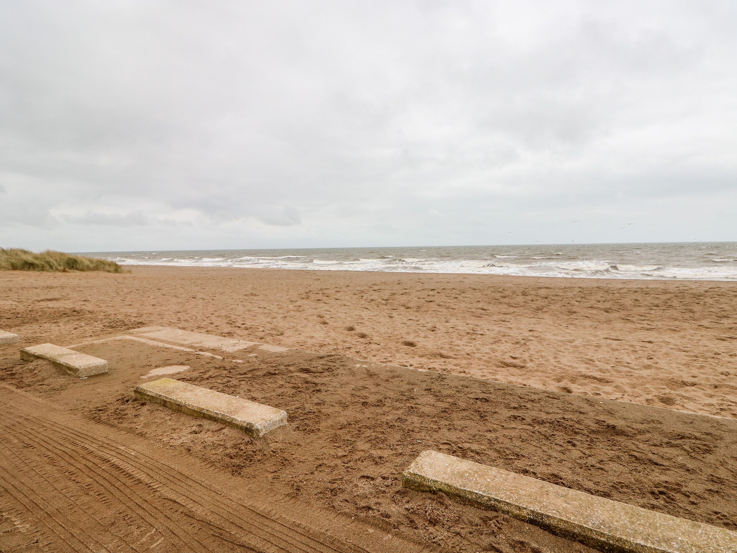 Ein Sandstrand unter bewölktem Himmel.