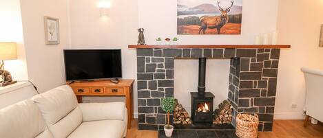 A living room with a stone fireplace, a television, a sofa, and a painting of an elk.