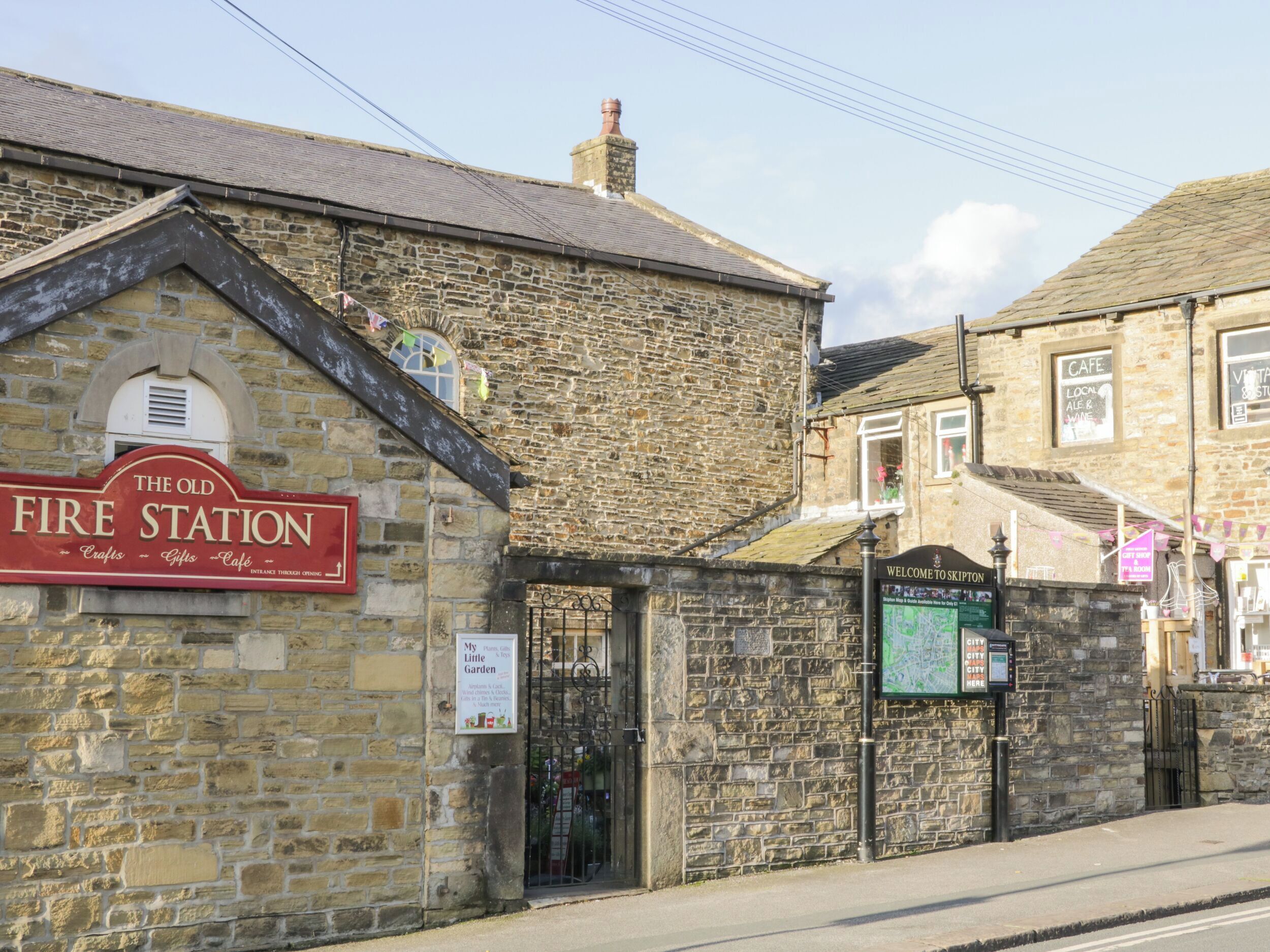 A stone building with a sign reading "The Old Fire Station" and another sign welcoming visitors to Skipton.