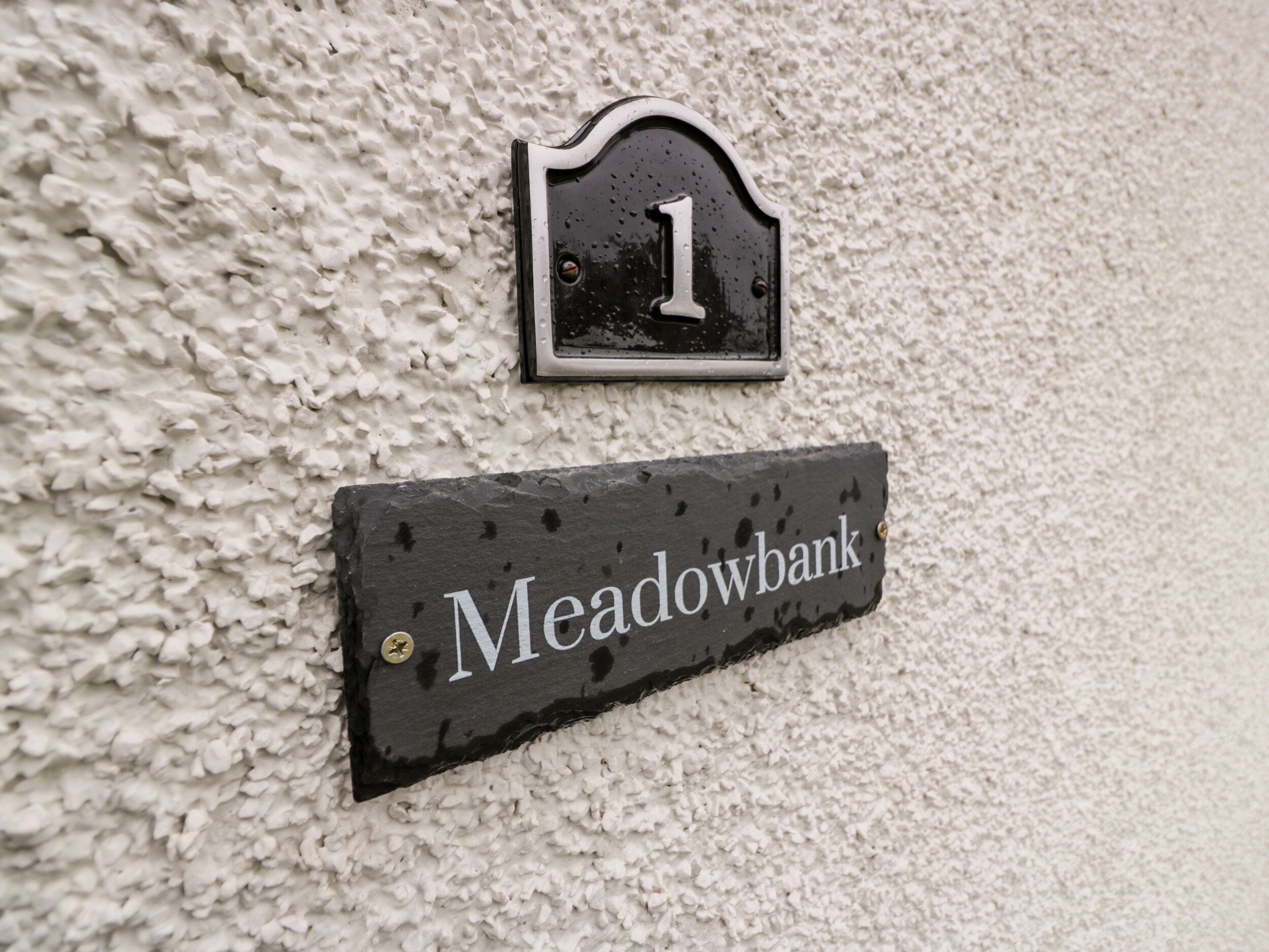 A house number '1' and a nameplate 'Meadowbank' mounted on a textured wall.