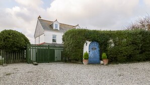 A house with a gravel driveway, a blue gate, and a white fence. - Trevena Lodge (Tintagel)