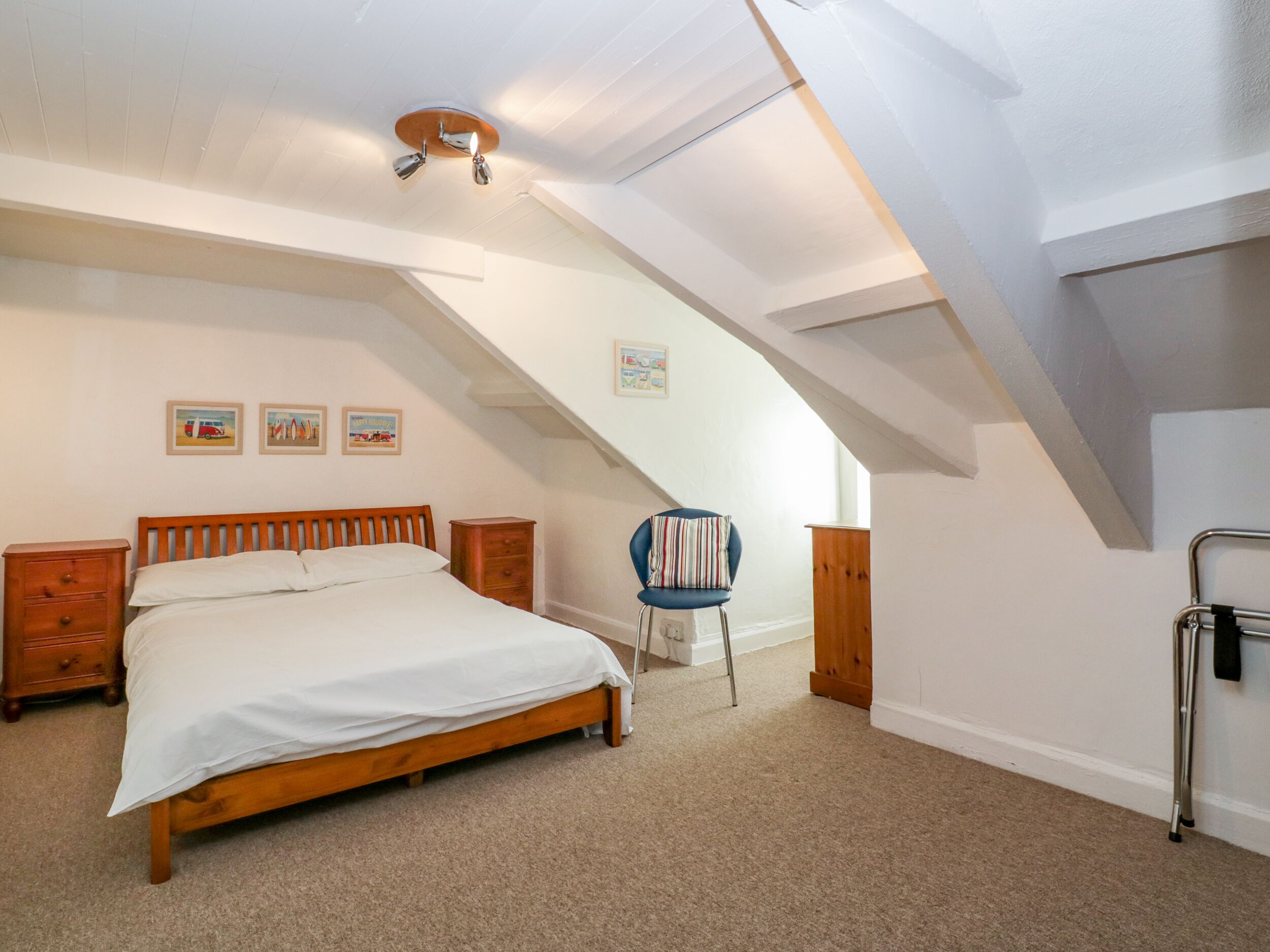 A bedroom with a wooden bed, a nightstand, a chair, and a ceiling fan.