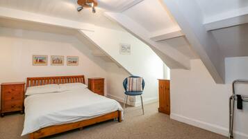 A bedroom with a wooden bed, a nightstand, a chair, and a ceiling fan.
