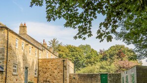 A stone building with a gravel courtyard, a green door, and a bench.