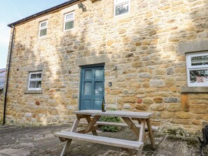 A stone building with a blue door, a wooden bench, and a small table. - Todridge Barn (Newcastle-upon-Tyne)