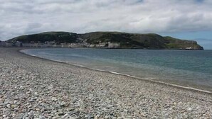 Een kiezelstrand met uitzicht op een kustplaatsje en kliffen.