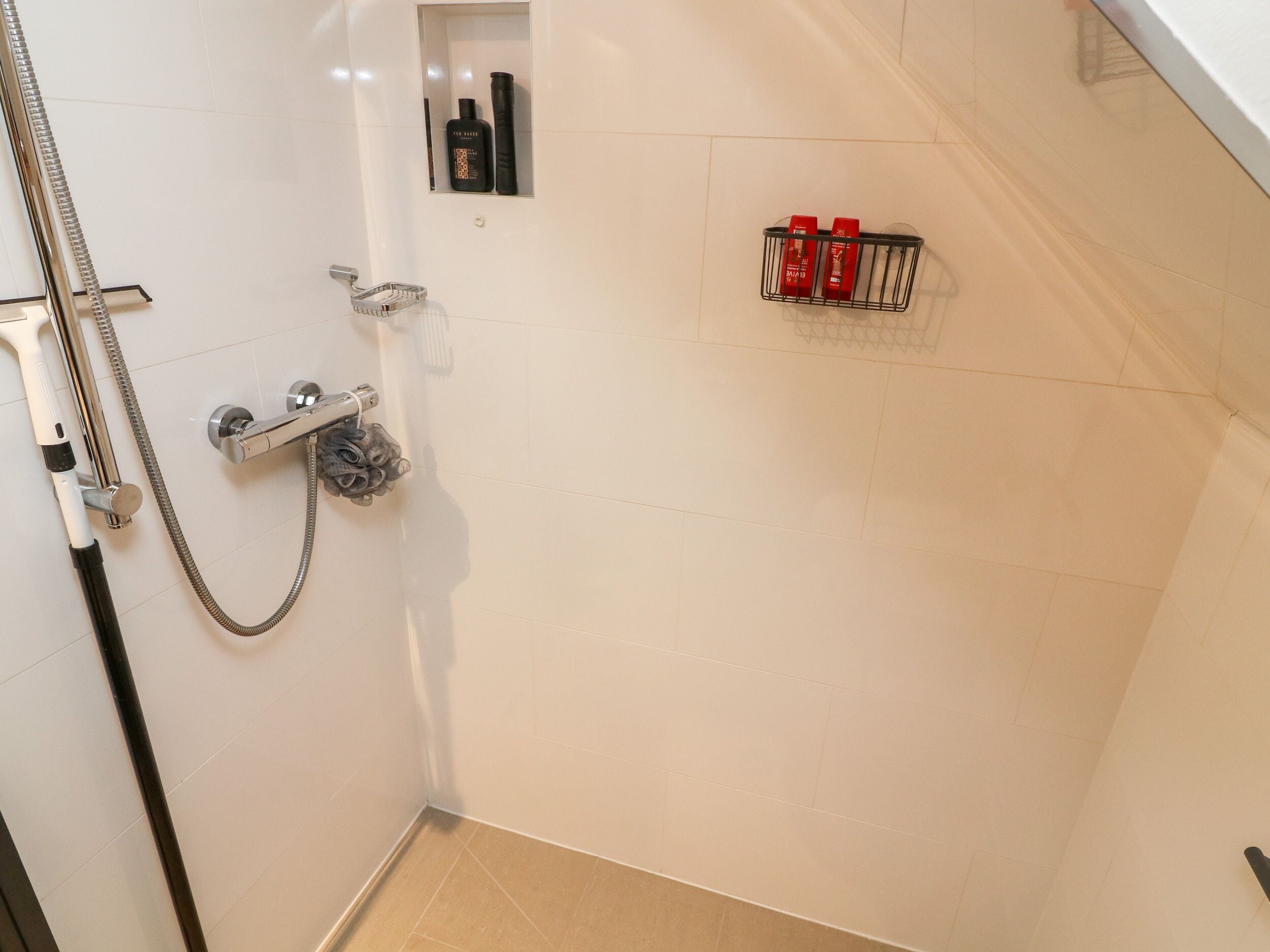 A shower area with a handheld showerhead, a wall-mounted faucet, and a towel rack.