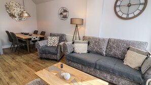 Un salon moderne avec un canapé gris, une table basse en bois et un coin repas comprenant une table et des chaises.