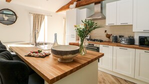 Una cocina moderna con vigas de madera, armarios blancos, una isla grande y una variedad de electrodomésticos.