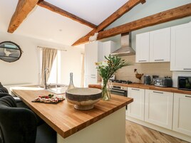A modern kitchen with wooden beams, white cabinets, a large island, and a variety of appliances.