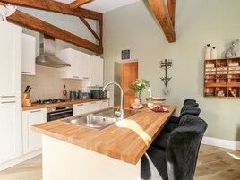 A kitchen with wooden beams, white cabinets, a wooden countertop, a sink, and a breakfast bar.