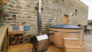 Edificio rústico de piedra con estufa de leña, un barril de madera grande y un cartel que dice 'Save Water Drink Beer'.