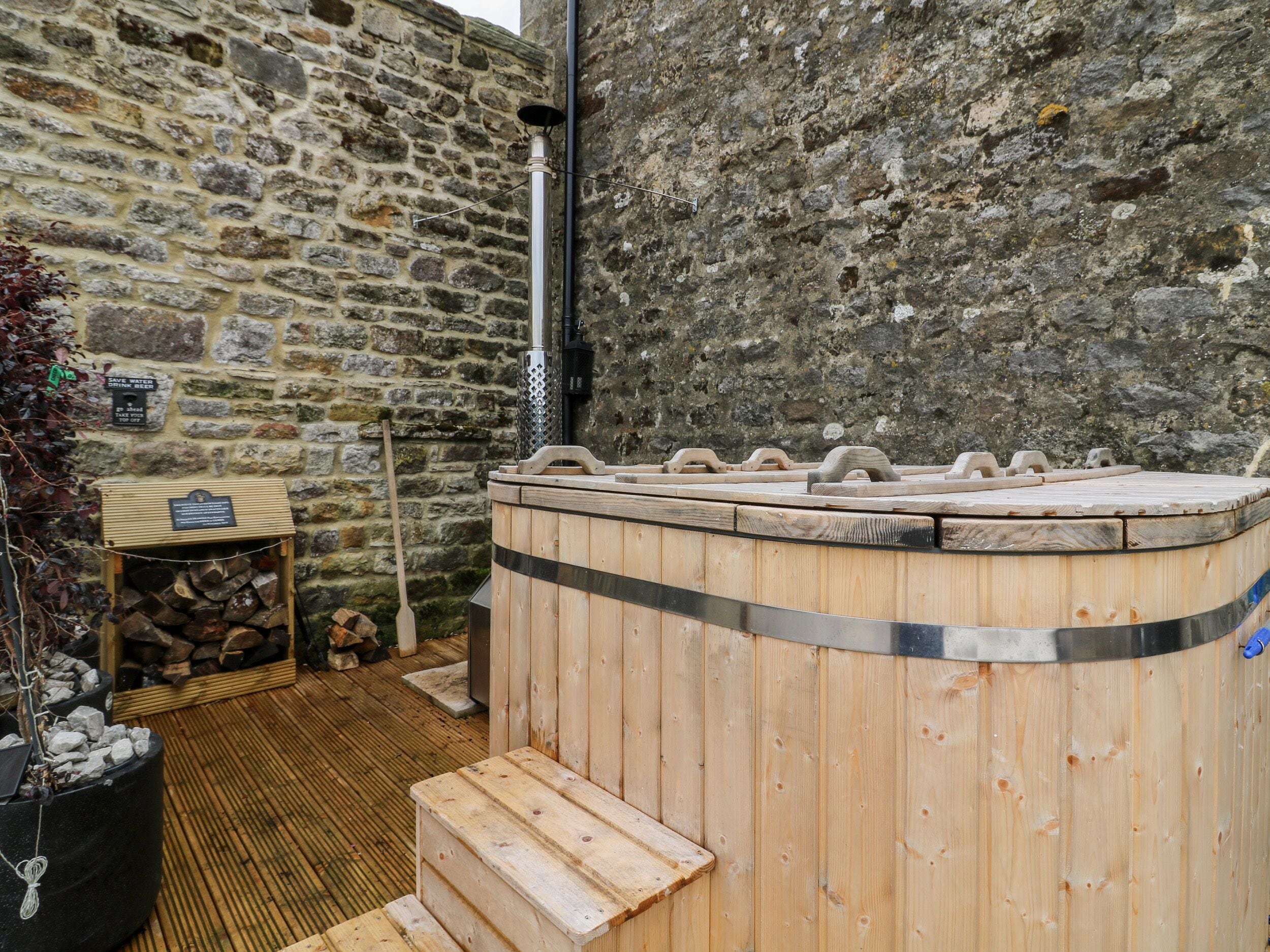 A stone-walled sauna area with a wooden bench and a log storage box.