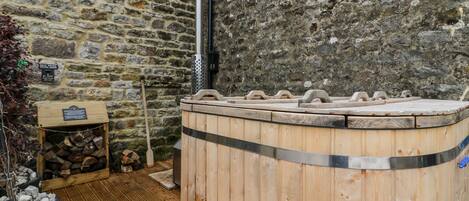 A stone-walled sauna area with a wooden bench and a log storage box.