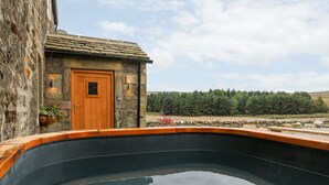 A stone building with a wooden door and a small window, surrounded by a stone wall and a wooden deck. - Skyfell (Skipton)