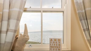 A window with a view of a body of water, curtains, and a sign with text. - Skyfell (Skipton)