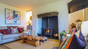 A living room with a sofa, a coffee table, a fireplace, and a painting on the wall. - Cefn Nannau (Corwen)
