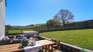 A patio with a table, chairs, and a hot tub. - Cefn Nannau (Corwen)