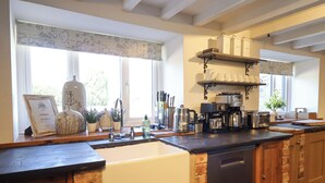 A kitchen with a large island, built-in dishwasher, and a coffee station. - Cefn Nannau (Corwen)