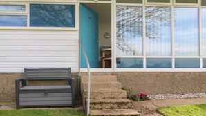 Una casa con puerta azul, un banco en el exterior y un conjunto de escaleras que llevan a la entrada.