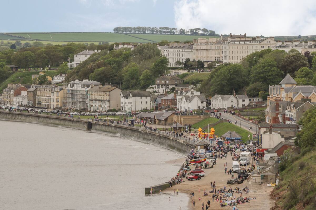 A coastal town with a promenade, buildings, and a bridge.