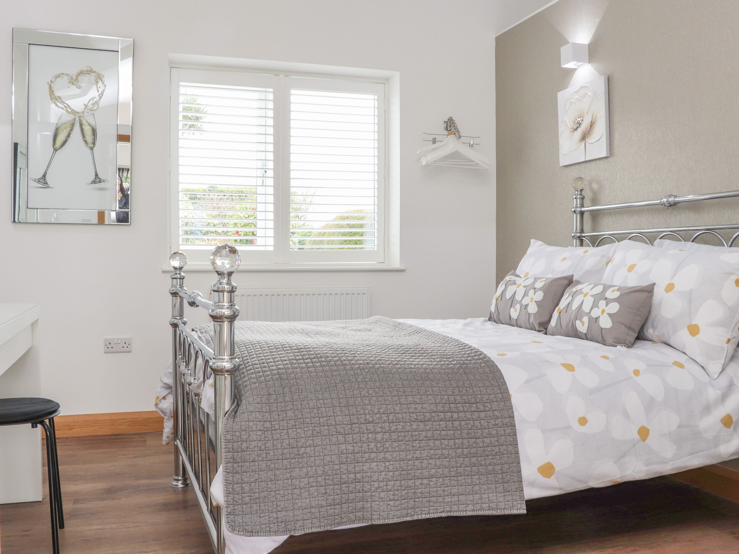 A bedroom with a bed, a window, a wall-mounted light, and a framed picture.
