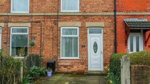 A two-story brick house with a white front door, a small garden, and a wooden fence. - Hazelmere Cottage (Worksop)