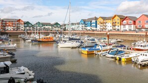 A marina with various boats docked, surrounded by colorful buildings. - Sea Point (Exmouth)