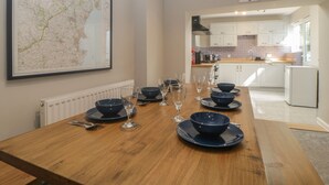 A dining table set with bowls and wine glasses, a map on the wall, and a kitchen in the background.