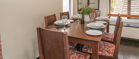 A dining table set with plates, glasses, and a vase of tulips.