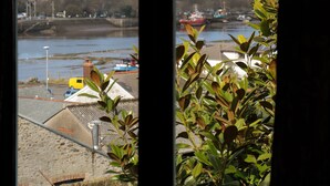 Vista attraverso una finestra, con un fiume, imbarcazioni ed edifici sullo sfondo.