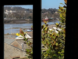 Blick durch ein Fenster auf einen Fluss, Boote und Gebäude im Hintergrund.