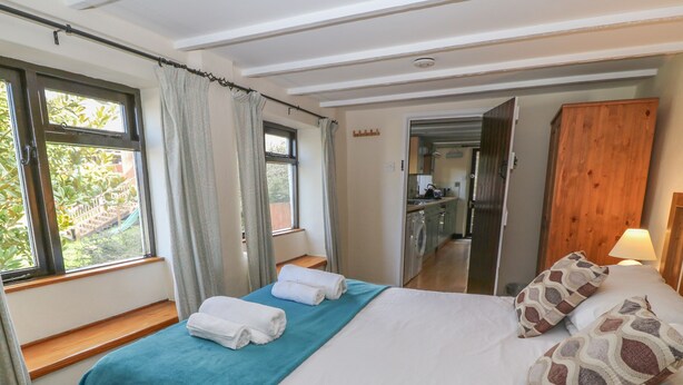Una camera da letto con un letto, una panca e vista su cucina e giardino.