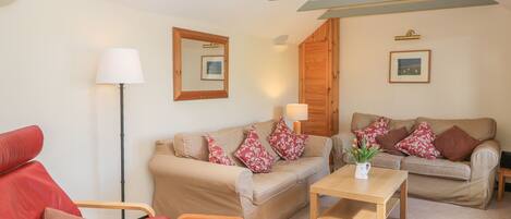 A living room with two sofas, a wooden coffee table, and a red armchair.