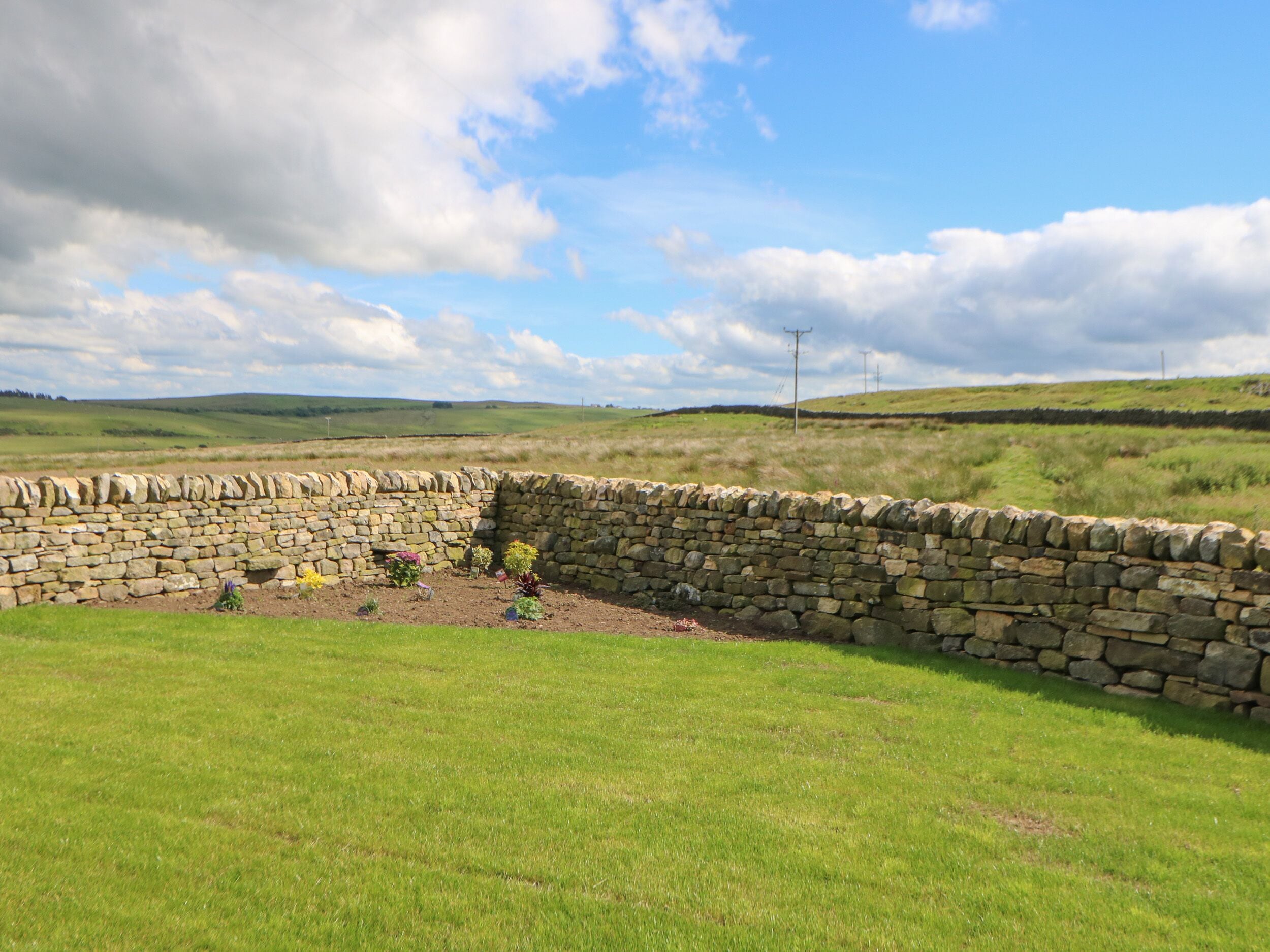 A stone wall with a grassy field and a clear sky.